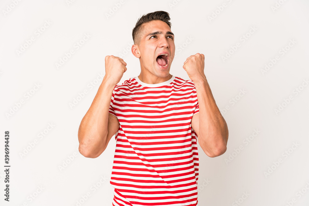 Young caucasian handsome man isolated raising fist after a victory, winner concept. Young caucasian handsome man isolated raising fist after a victory, winner concept.