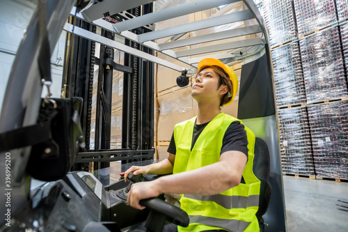 Focused asian warehouse worker with forklift at work