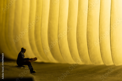 old man reading a book in front of a light