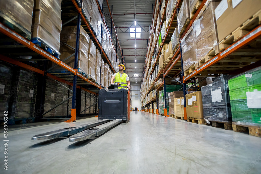 Forklift operator during work in large warehouse drives between shelves