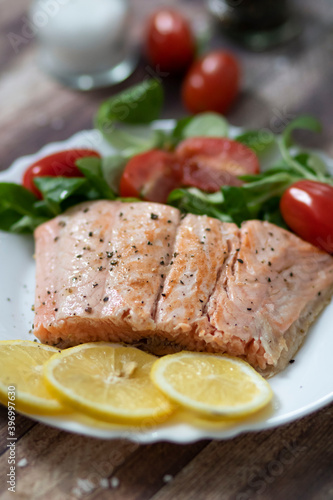 Salmon in a pan with lemon and other vegetables. Salmon on plates