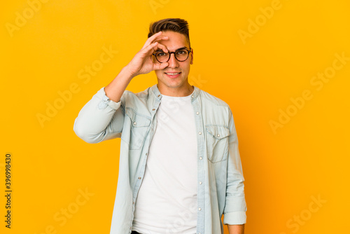 Young handsome caucasian man isolated excited keeping ok gesture on eye.