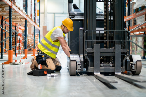 Photos Mechanic repairing forklift in warehouse