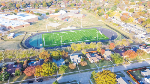 Top view school football field with running track, soccer goal, artificial playing surface and colorful autumn leaves near Dallas, Texas