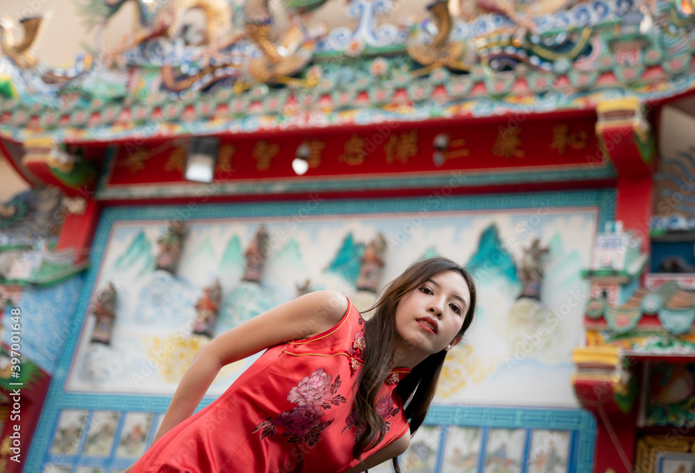 Asian woman wearing red Cheongsam dress at Chinese shrine. Chinese new year concept.