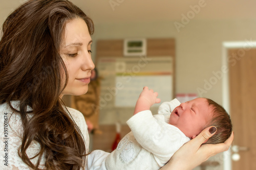 Beautiful young mother holding her newborn baby boy after labor in hospital. Mother giving birth to child. Newborn baby in delivery room. Parent and infant first moments of bonding. Happy mother s day