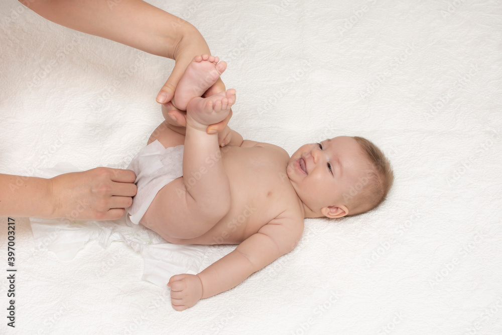 Close up of mother cleaning up baby by wet tissue when changing nappies or diaper in white nursery with bed. Hygiene concept. Cleaning wipe, pure. Close up of mother cleaning up baby by wet tissue when changing nappies or diaper in white nursery with bed. Hygiene concept. Cleaning wipe, pure.