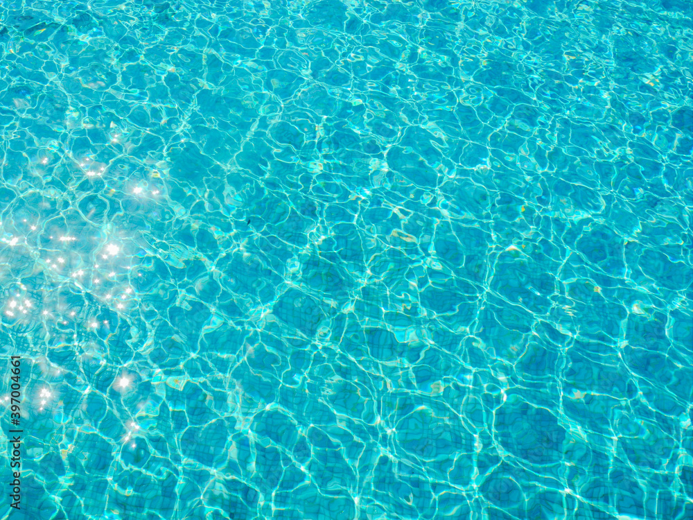 Вода в бассейне голубого цвета переливается на солнце и блестит