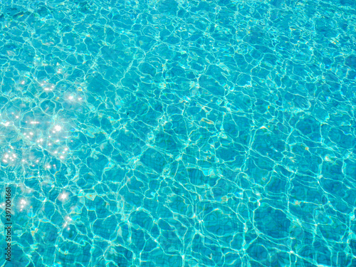 Вода в бассейне голубого цвета переливается на солнце и блестит