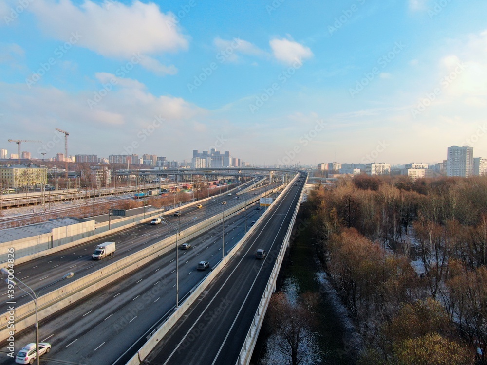 Aerial view flight over a high-speed highway in a big city at dawn. Movement of cars through the streets of the city Aerial view flight over a high-speed highway in a big city at dawn. Movement of cars through the streets of the city