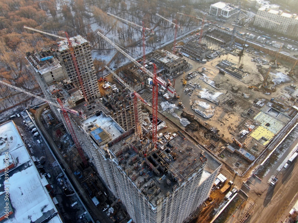 Fototapeta premium Aerial view construction of a modern office building. The work of building tower cranes against the background of the cityscape