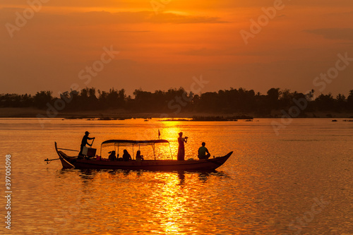 DOLPHIN WATCHING, MEKONG RIVER, KRATIE PROVINCE, CAMBODIA - 31 January 2012: Tourist on boat at sunset tries to photograph the elusive irrawaddy dolphin. photo