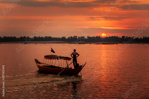 DOLPHIN WATCHING, MEKONG RIVER, KRATIE PROVINCE, CAMBODIA - 31 January 2012: Local dolphin watch boat opperator watches beautiful sunset at end of his day. photo