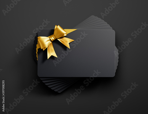 Fotografía Stack of black credit or gift cards with golden ribbon isolated on dark backgrou