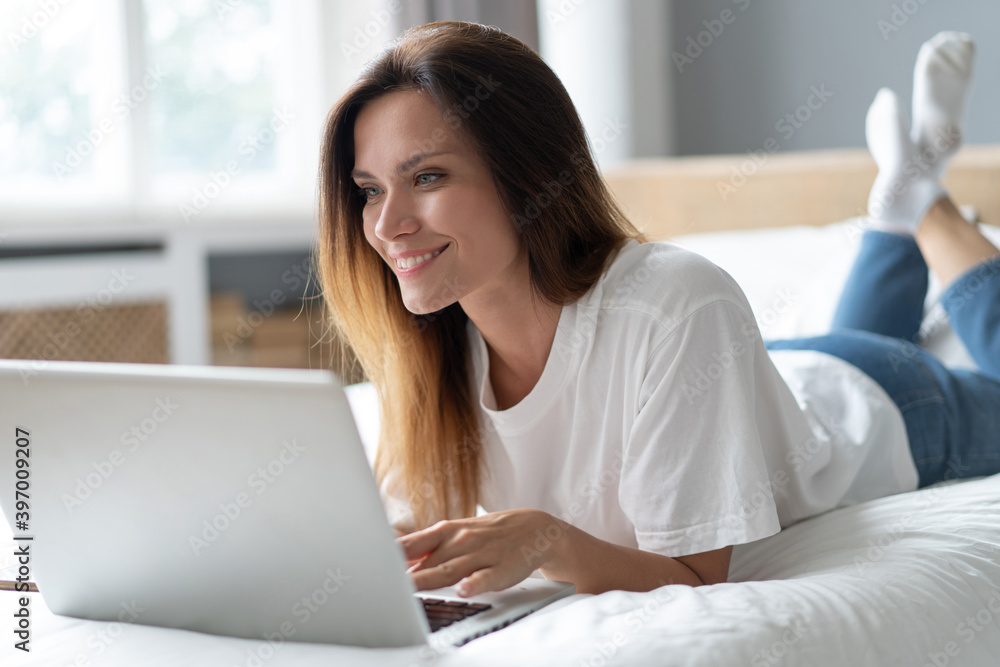 Portrait of a beautiful smiling young woman using laptop in bed at home. Portrait of a beautiful smiling young woman using laptop in bed at home.