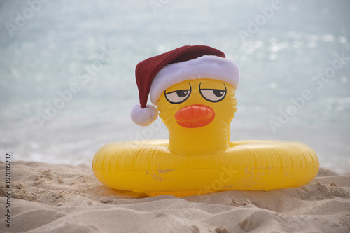 
YELLOW INFLATABLE LIFEGUARD DUCK WITH SANTA CLAUS HAT ON THE SHORES OF A CARIBBEAN BEACH ON A SUNNY DAY