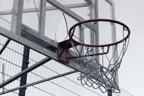 An old broken basketball basket with broken glass and torn mesh. Bad conditions for sports concept photo. Vandalism.