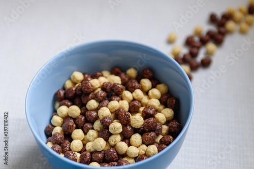 Bowl with chocolate and milk balls and a glass of milk on the table.