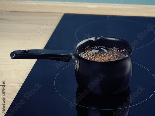 coffee is brewed in Cezve on a modern induction cooker. photo