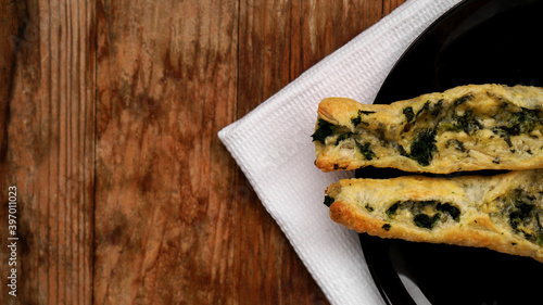 Rollini with brynza cheese and spinach on a black plate with a wooden background photo