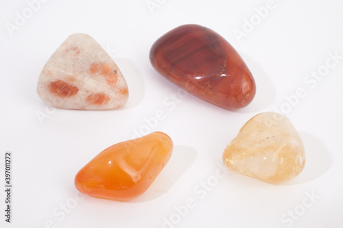 A selection of sacral chakra healing gemstones against a white background