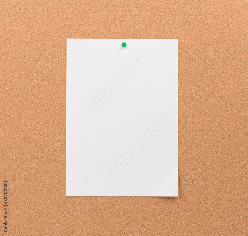blank white sheet of paper attached with green button on a brown background
