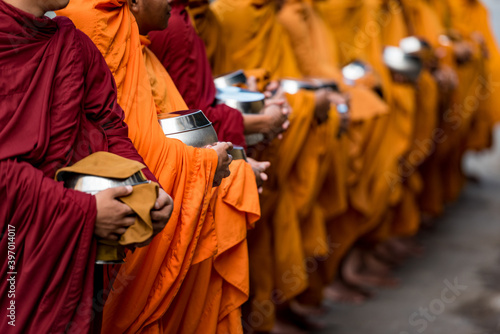 MONKS DOING ALMS, BATTAMBANG, CAMBODIA - 17 December 2014: Long line of begging bowls expecting donations of rice in support of monks spiritual quest.