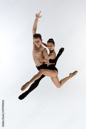 Ballet jump. Young and graceful ballet dancers in black style isolated on white studio background. Art, flexibility, inspiration, lightness of the body concept. Flexible caucasian ballet dancers.