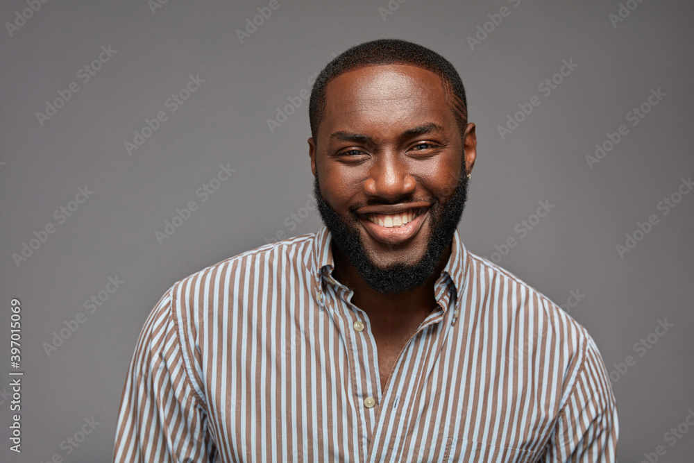 Obraz premium Young cheerful handsome African american man smiling against grey background