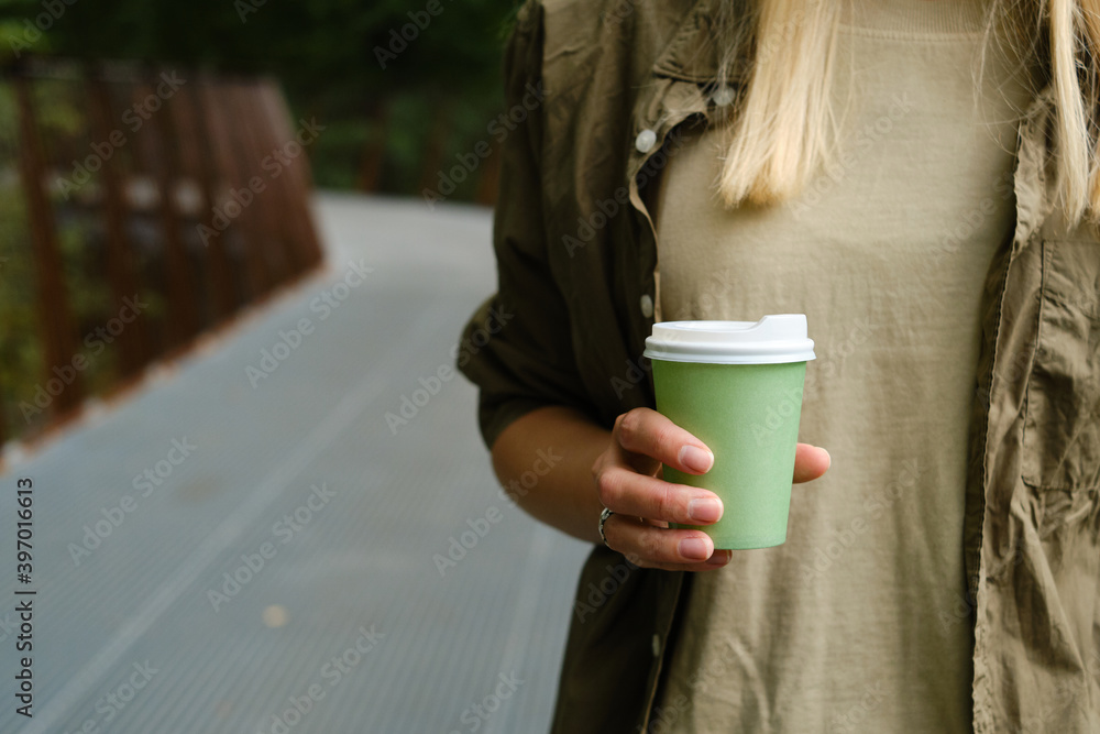 Green paper cup with coffee in woman hand. Time for drink coffee in city. Coffee to go. Enjoy moment, take a break. Disposable paper cup closeup. Delicious hot beverage. Blank space for text, mockup Green paper cup with coffee in woman hand. Time for drink coffee in city. Coffee to go. Enjoy moment, take a break. Disposable paper cup closeup. Delicious hot beverage. Blank space for text, mockup