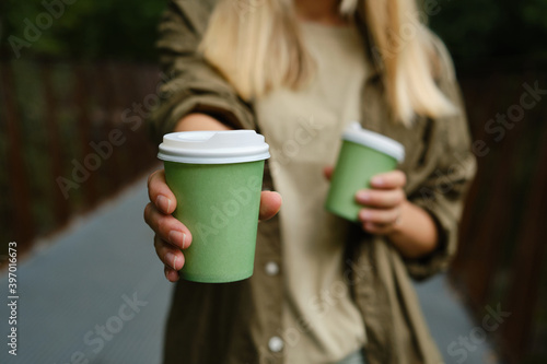 Green paper cup with coffee in woman hand. Time for drink coffee in city. Coffee to go. Enjoy moment, take a break. Disposable paper cup closeup. Delicious hot beverage. Blank space for text, mockup