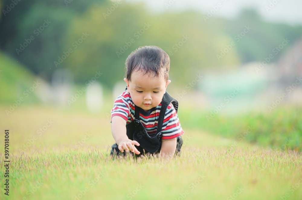 Cute laughing baby boy having fun sitting on green grass Cute laughing baby boy having fun sitting on green grass