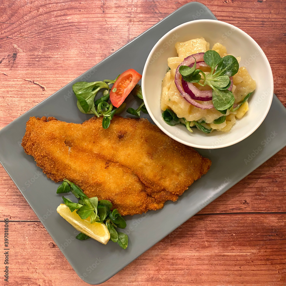 Golden breaded fish plaice fillet with potato salad and lemon. Stock ...