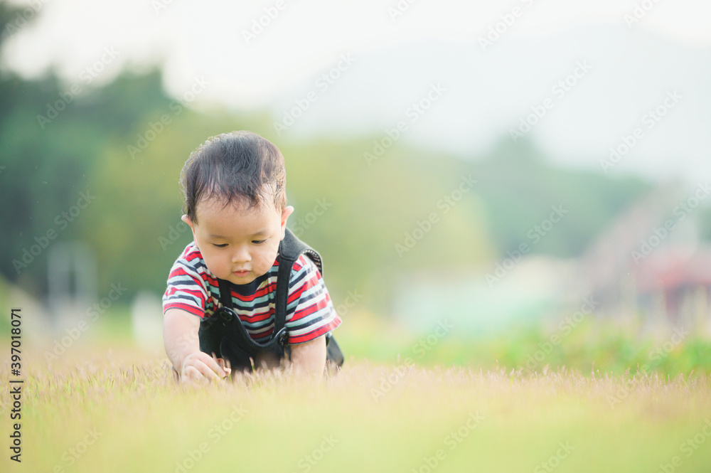 Cute laughing baby boy having fun sitting on green grass Cute laughing baby boy having fun sitting on green grass