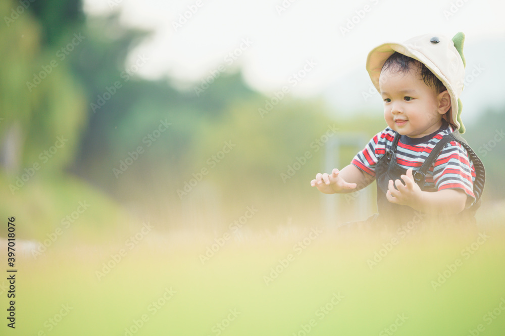 Cute laughing baby boy having fun sitting on green grass Cute laughing baby boy having fun sitting on green grass