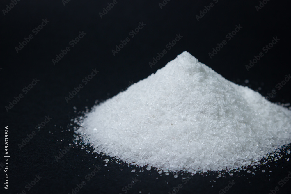 Heap of salt on a black background. Excessive salt intake. Coarse salt