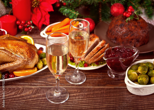 Table served for thanksgiving or Christmas dinner. Two glasses of wine or champagne. Stuffed roasted turkey, pudding and ham. Traditional celebrating holiday. Top view.