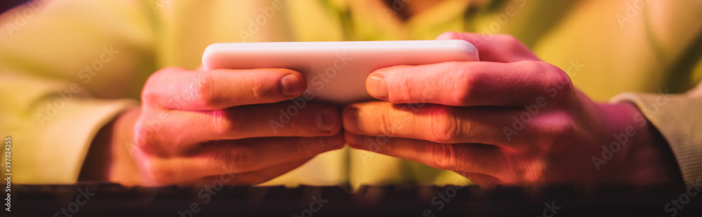 Cropped view of gamer playing video game on smartphone, banner
