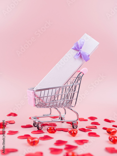 Shopping trolley with gift box, red hearts. Valentine's day gift shopping concept