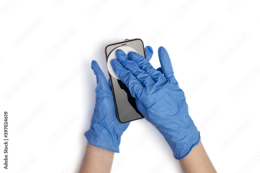 Hands in medical gloves wipe the smartphone screen with a disinfectant cloth. Close up of hands are cleaning mobile phone isolated on white background. Smartphone disinfection Hands in medical gloves wipe the smartphone screen with a disinfectant cloth. Close up of hands are cleaning mobile phone isolated on white background. Smartphone disinfection