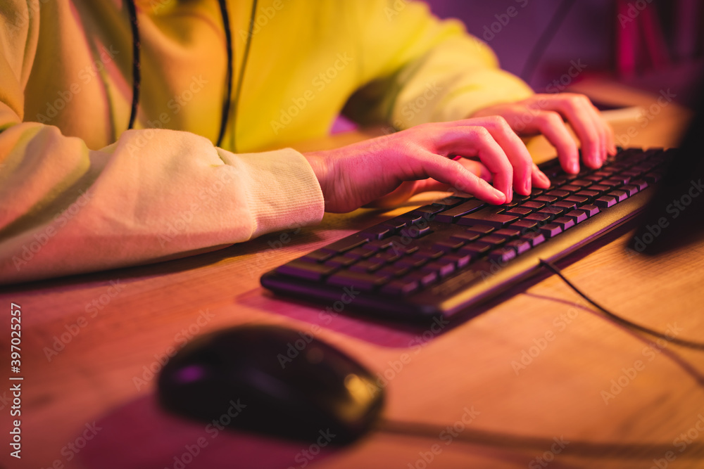 Cropped view of gamer using computer keyboard near mouse on blurred foreground Cropped view of gamer using computer keyboard near mouse on blurred foreground