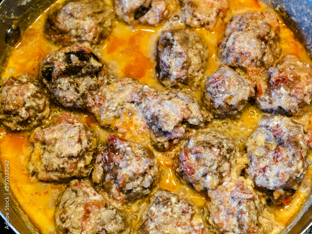 above view of meatballs are stewed in tomato and cream sauce in saucepan at home kitchen