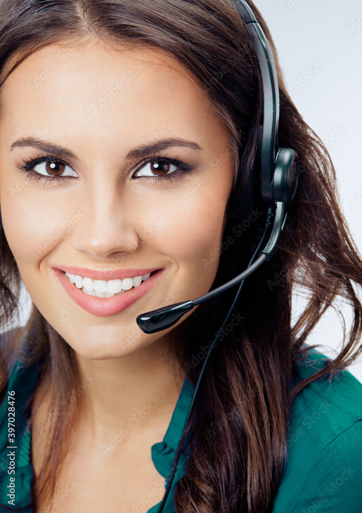 Happy smiling female phone operator in headset, green confident clothing, over grey background. Call center and customer support service concept. Studio portrait image. Happy smiling female phone operator in headset, green confident clothing, over grey background. Call center and customer support service concept. Studio portrait image.