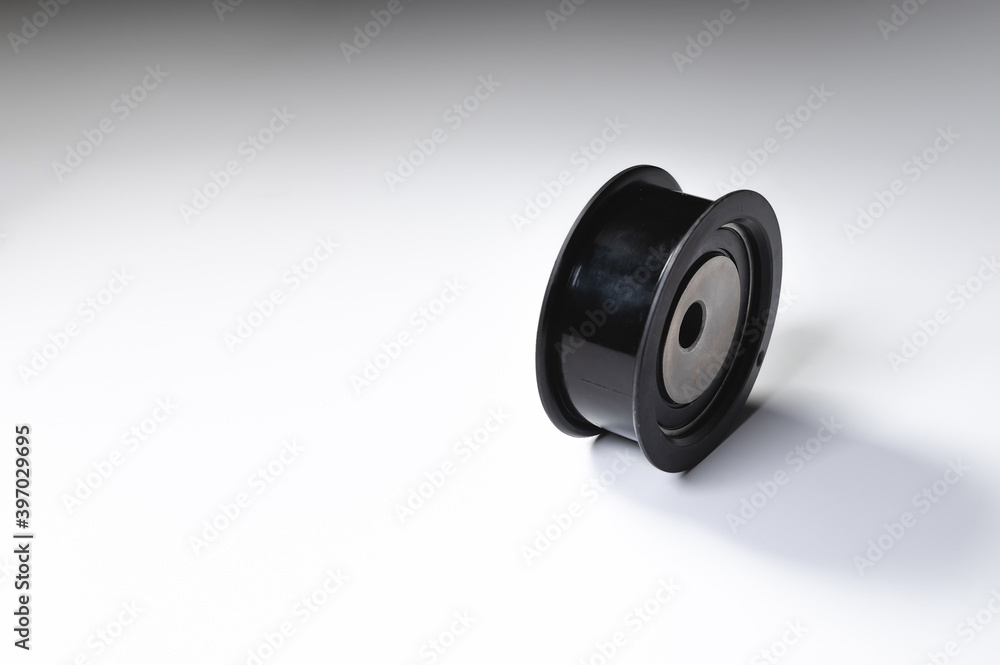 New timing belt tensioner roller close-up macro shot on gray background New timing belt tensioner roller close-up macro shot on gray background