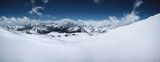 Alpine panorama of the snow-covered Great Caucasus Range on a sunny day with variable cloud cover. Ideal panoramic slopes for skiing, freeriding, skiing and snowboarding