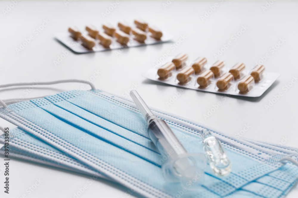Medical face mask, packaging with pills, ampulla and expendable syringe for vaccination. Coronavirus vaccination concept. COVID-19 outbreak. Medical face mask, packaging with pills, ampulla and expendable syringe for vaccination. Coronavirus vaccination concept. COVID-19 outbreak.