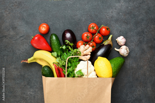 Fototapeta Naklejka Na Ścianę i Meble -  Fresh vegetables, fruit and greens in craft paper shopping bag on black rustic background. Eco shopping and food delivery concept.  A concept of proper nutrition delivery.