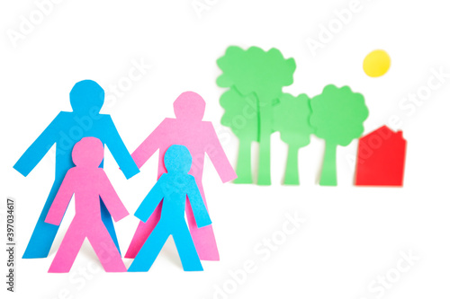 Conceptual image of paper cut out shapes representing a family with trees and house over white background