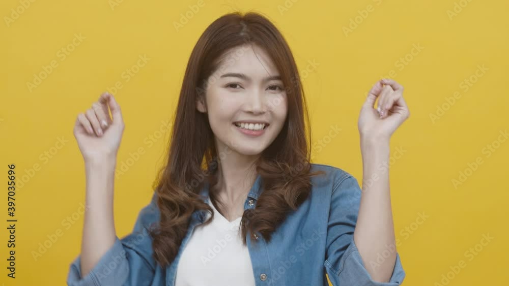 Portrait of asian young woman wearing white shirt and blue jean jecket feeling funny, enjoy and active dance. Asian woman on yellow background studio shot Portrait of asian young woman wearing white shirt and blue jean jecket feeling funny, enjoy and active dance. Asian woman on yellow background studio shot