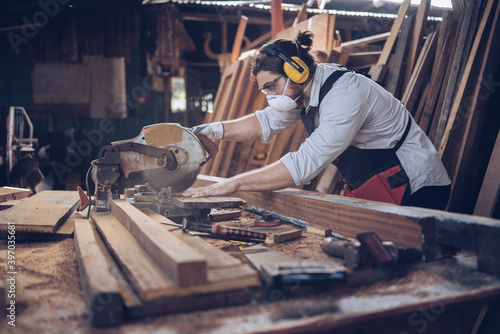 Carpenter man cutting wood with saw. craftsman working workshop factory industry.  Capenter worker with mask protection. photo